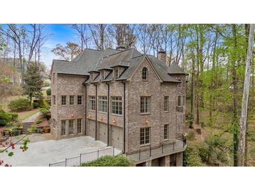 Elegant brick home with multiple garage doors and beautiful architectural details surrounded by lush greenery at 115 Mount Paran Rdg, Atlanta, GA 30327
