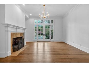 Bright living room with hardwood floors, fireplace, chandelier, and French doors to the backyard at 115 Mount Paran Rdg, Atlanta, GA 30327