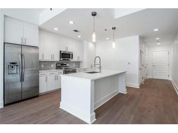 Modern kitchen features stainless steel appliances, white cabinets, and a spacious island with pendant lighting at 1080 Peachtree Ne St # 1504, Atlanta, GA 30309
