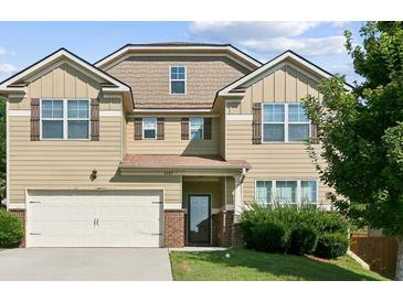 Charming two-story home with a tan exterior, a two-car garage, shuttered windows, and well-maintained landscaping at 5243 Cantbury Way, Atlanta, GA 30349
