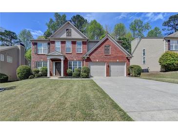 Charming two-story brick home with a well-manicured lawn and two-car garage on a sunny day at 580 Hammersmith Dr, Suwanee, GA 30024