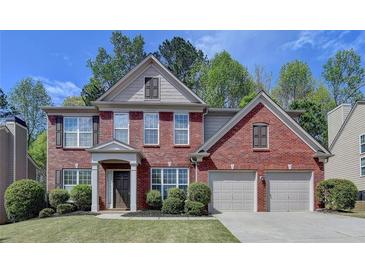 Charming two-story red brick home with a well-maintained lawn, two-car garage and neutral trim at 580 Hammersmith Dr, Suwanee, GA 30024