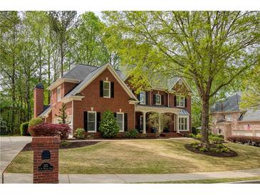 Beautiful two-story brick home with mature trees and a well-manicured lawn in a suburban neighborhood at 325 N Saint Phillip Ln, Alpharetta, GA 30022