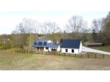 Charming farmhouse with a dark metal roof and white siding, surrounded by a rustic wooden fence at 85 Carroll Slough Rd, Kingston, GA 30145