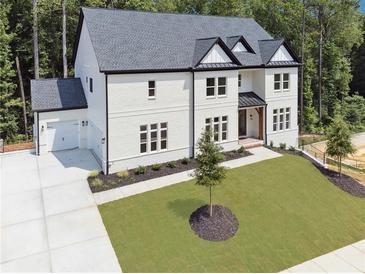 Stunning two-story painted brick home with a dark roof, lush lawn, and an attached two car garage at 3930 Clifton Hill Court #15, Cumming, GA 30040