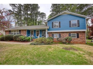 Charming two-story home with a brick facade, blue siding, and a well-manicured lawn with mature trees at 493 James Street Sw, Lilburn, GA 30047