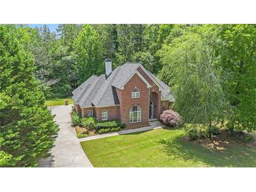 Beautiful brick home featuring a well-manicured lawn and mature trees, offering great curb appeal at 1418 Brighton Pl, Loganville, GA 30052