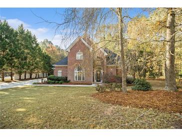 Charming two-story brick home featuring a well-manicured lawn and mature trees at 1418 Brighton Pl, Loganville, GA 30052