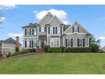 Charming two-story home featuring manicured landscaping, gray siding, and black shutters under a partly cloudy sky at 295 Sagamore Nw Cv, Sugar Hill, GA 30518
