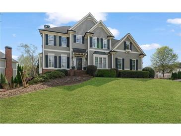 Stately two-story home featuring a manicured lawn, gray siding, and dark shutters at 295 Sagamore Nw Cv, Sugar Hill, GA 30518