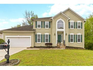 Charming two-story home featuring a well-manicured lawn, attached garage, and complementary green window shutters at 7415 Marina Cv, Stone Mountain, GA 30087