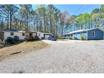 Exterior shot of two homes with mature trees and gravel driveway on a sunny day at 5955 Kemp Dr, Acworth, GA 30102