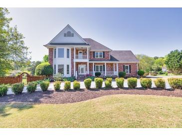 Stately brick home featuring a manicured lawn, mature landscaping, and classic architectural details under a clear blue sky at 1135 Azalea Cir, Conyers, GA 30013
