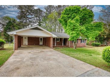 Charming brick home featuring a spacious driveway and a welcoming carport at 1311 Maple Street Se, Conyers, GA 30013