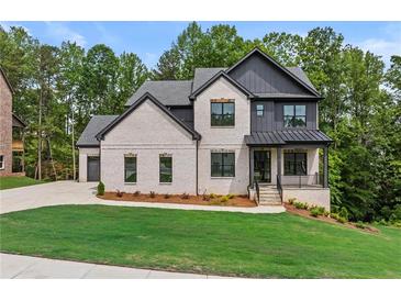Charming two-story home with brick and siding, a manicured lawn, and mature trees at 6132 Hutchins Dr, Buford, GA 30518