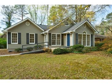 Charming single-story home with blue front door, ramp access, gray siding, and dark shutters, surrounded by lush landscaping at 2867 Payton Ne Rd, Atlanta, GA 30345