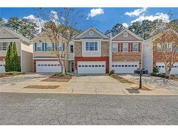 Charming townhomes with attached garages and brick and stone exteriors line a cozy neighborhood street at 545 Woodland Park Ter, Lawrenceville, GA 30043