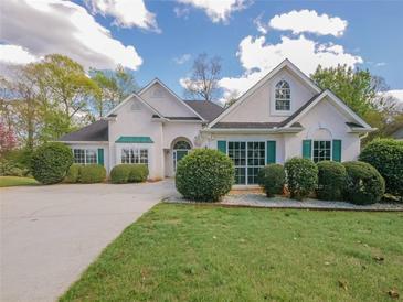 Charming one-story home with stucco exterior, green shutters, well-manicured landscaping, and concrete driveway at 334 Royal Crescent Way, Stockbridge, GA 30281