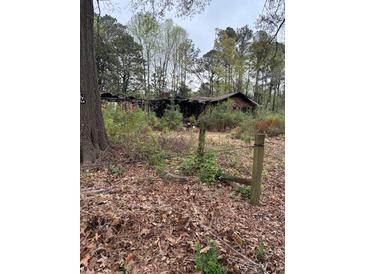 A damaged, one-story brick home, partially obscured by overgrown foliage, and in need of extensive renovation at 4216 Connor Dr, Ellenwood, GA 30294