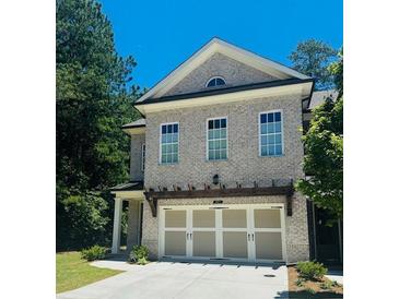 Two-story home featuring a light brick facade and a two-car garage with a pergola above it at 134 Wards Crossing Way # 17, Johns Creek, GA 30022