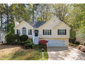 Charming home with a manicured lawn, complemented by beautiful landscaping and a welcoming front porch at 3027 Clove Tree Ln, Woodstock, GA 30189