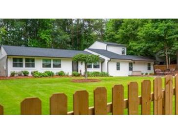 Charming single-story home with a lush green lawn and a classic picket fence in a serene, wooded neighborhood at 3785 Somerset Sw Dr, Marietta, GA 30064