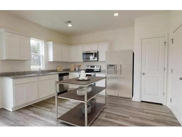 A spacious kitchen features white cabinets, granite countertops, stainless steel appliances, and an island at 7763 Sudbury Cir, Covington, GA 30014