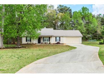 Charming single-story home featuring a metal roof, well-maintained lawn, and a paved driveway leading to an attached garage at 85 Emily Trce, Covington, GA 30016