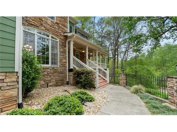 Stone and green siding with a covered porch and well-manicured landscaping welcomes you home at 104 Kremer Falls Trce, Canton, GA 30114