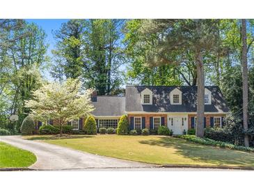 Charming two-story brick home with blue shutters and a lush front yard featuring a beautiful blossoming tree at 1000 N Harbor Ct, Atlanta, GA 30328