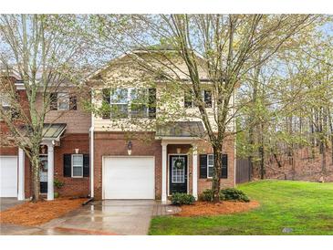Charming brick townhome with a one-car garage, small porch, and manicured front lawn with fresh pine straw at 3065 Windcrest Ct, Alpharetta, GA 30022