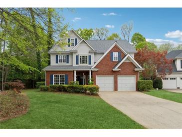 Charming two-story home featuring a brick facade, gray siding, a well-manicured lawn, and an attached two-car garage at 310 Kingspring Ct, Roswell, GA 30076