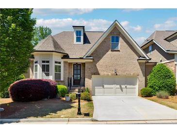 Charming brick home features a two-car garage, beautifully landscaped front yard, and dormer window at 95 Nesbit Reserve Ct, Alpharetta, GA 30022
