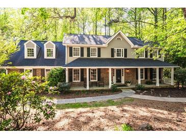 Charming brick home featuring a covered front porch and dormer windows surrounded by lush greenery at 2685 Hearthstone Cir, Marietta, GA 30062