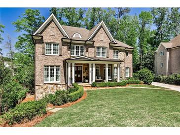 Charming two-story brick home featuring a manicured lawn, stone accents, and inviting covered front porch at 156 Lake Forrest Ne Ln, Atlanta, GA 30342