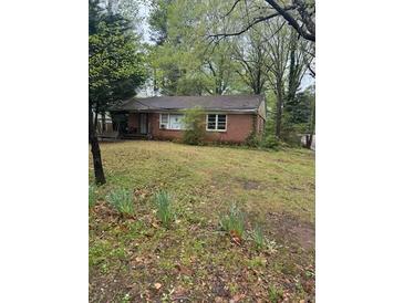 Charming one-story brick house with a porch surrounded by lush green foliage and a spacious front yard at 2667 Plantation Dr, Atlanta, GA 30344