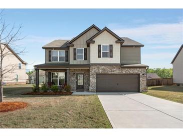 Charming two-story home with brick and siding, a well-manicured lawn, and an attached two-car garage at 336 Elaina Cir, Locust Grove, GA 30248