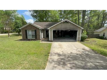 Modest single-story home with damaged garage and well-maintained front lawn at 100 Waters Edge Dr, Locust Grove, GA 30248