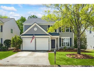 Charming two-story home featuring a two-car garage, manicured lawn, and mature tree in a suburban neighborhood at 512 Watercress Dr, Woodstock, GA 30188