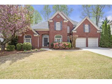 Charming two-story brick home featuring a well-manicured lawn, blooming flowers, and a two-car garage at 625 Park Creek Trce, Alpharetta, GA 30005