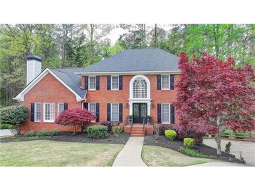 Charming red brick home with manicured lawn, mature trees, and beautiful landscaping at 3045 Hartridge Dr, Johns Creek, GA 30022