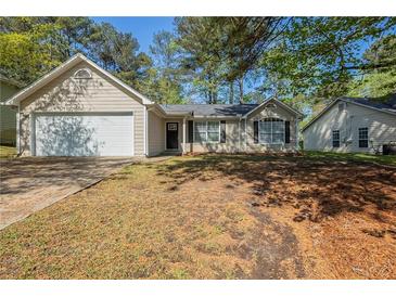 Charming single-story home with attached garage, manicured lawn, and mature trees at 6520 Emerald Pointe Cir, Atlanta, GA 30349
