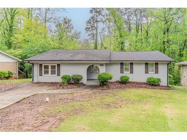 Charming single-story home featuring a light brick exterior and an arched entryway nestled in a lush green landscape at 2682 Cavalier Dr, Decatur, GA 30034