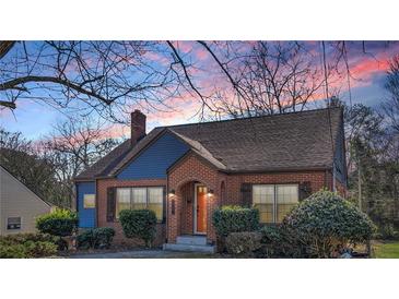 Charming brick home featuring an arched doorway and complemented by manicured landscaping at twilight at 958 Winburn Dr, Atlanta, GA 30344