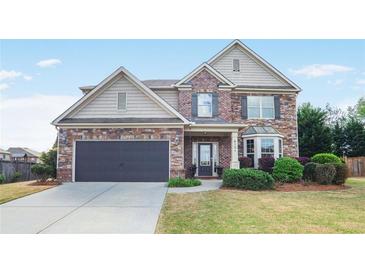 Charming two-story home with stone and siding exterior, landscaped lawn, and attached two-car garage at 415 Eldridge Dr, Suwanee, GA 30024