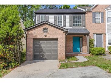 Charming two-story townhouse with a brick facade, attached garage, and a vibrant turquoise front door at 1379 Vintage Pointe Dr, Lawrenceville, GA 30044