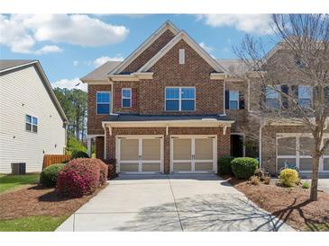 Brick front townhome with a two-car garage and blooming landscaping at 6270 Shiloh Woods Dr, Cumming, GA 30040