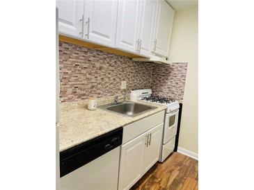 This kitchen features a gas range, tile backsplash and white cabinets at 2805 Ne Ne Expressway Ne # B-26, Atlanta, GA 30345