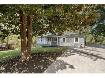Charming single-story home with light gray siding, green lawn and long driveway at 5725 Brenda Sw Dr, Mableton, GA 30126