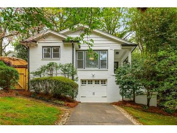 Charming white brick home with a well-manicured front yard, driveway, and attached one-car garage at 648 Channing Nw Dr, Atlanta, GA 30318